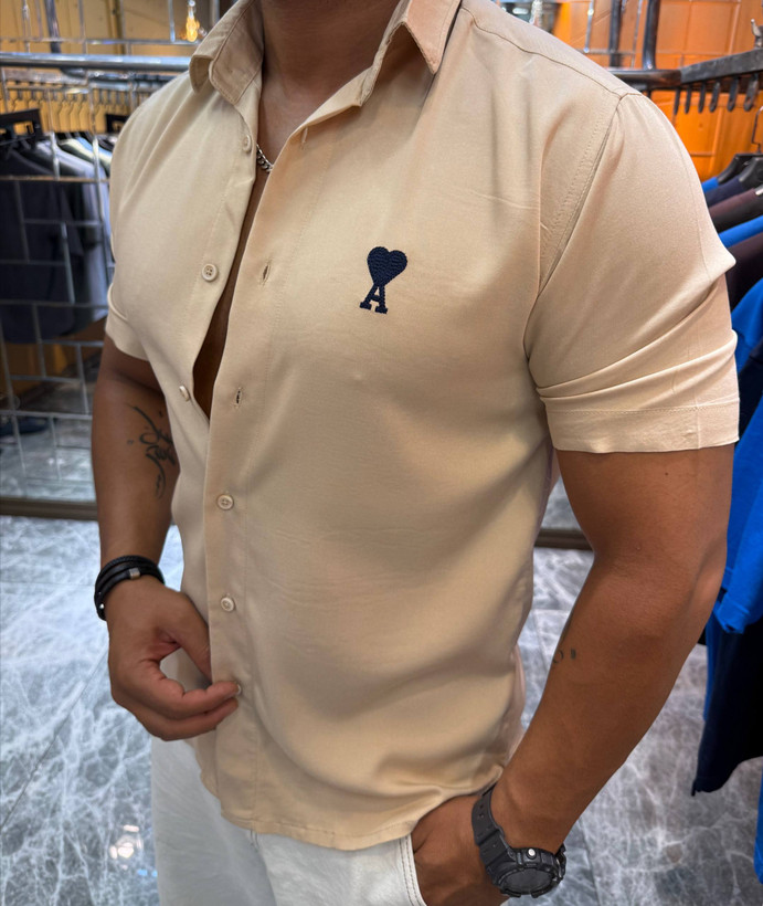 مدل مرد با پیراهن آستین کوتاه لینن لخت AMI رنگ کرم و لوگوی قلب روی سینه